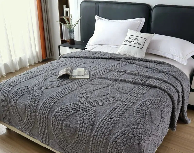 Gray textured blanket on a bed with white pillows in a bedroom setting