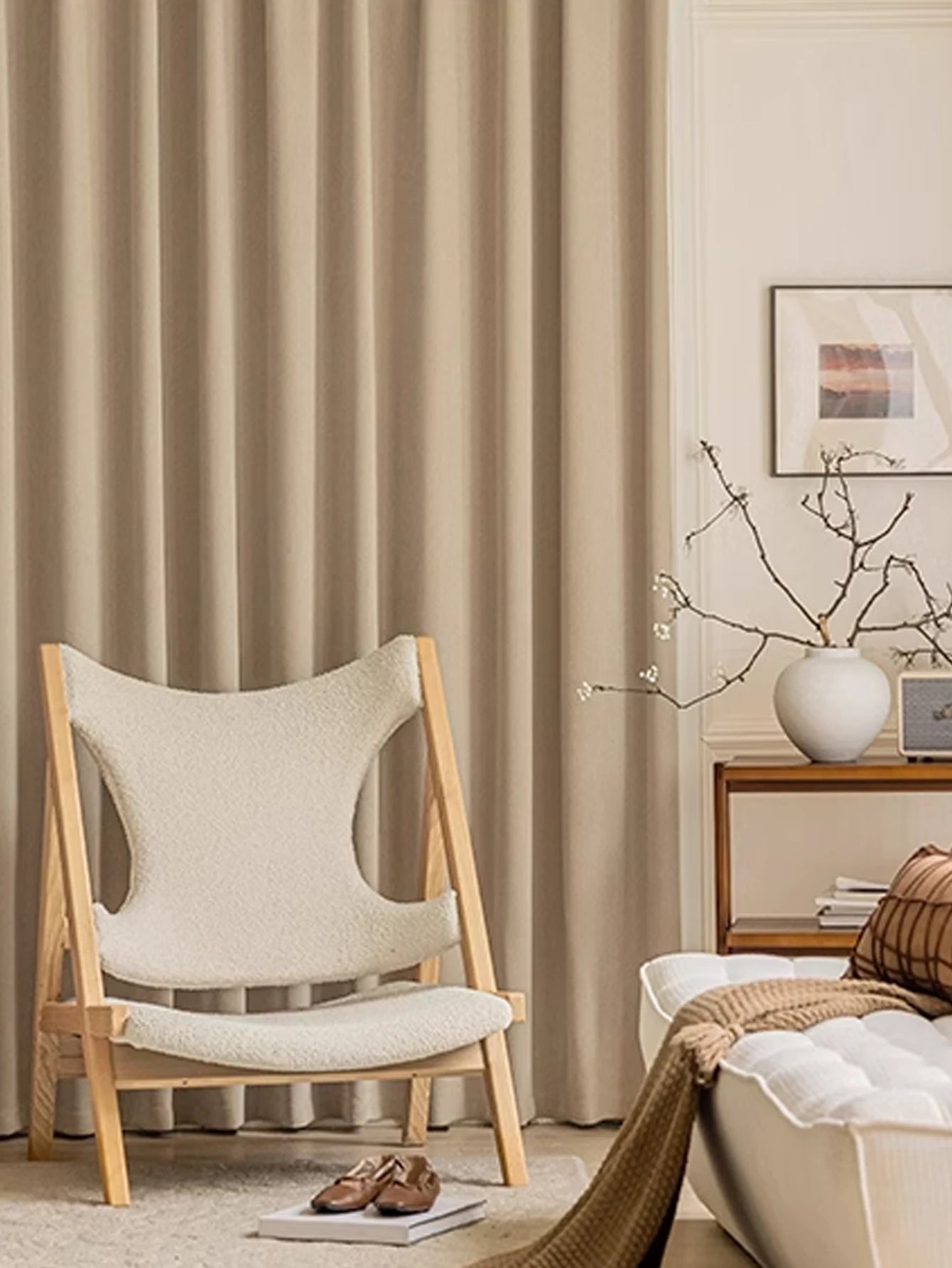 Beige chair in a living room with curtains and a side table.