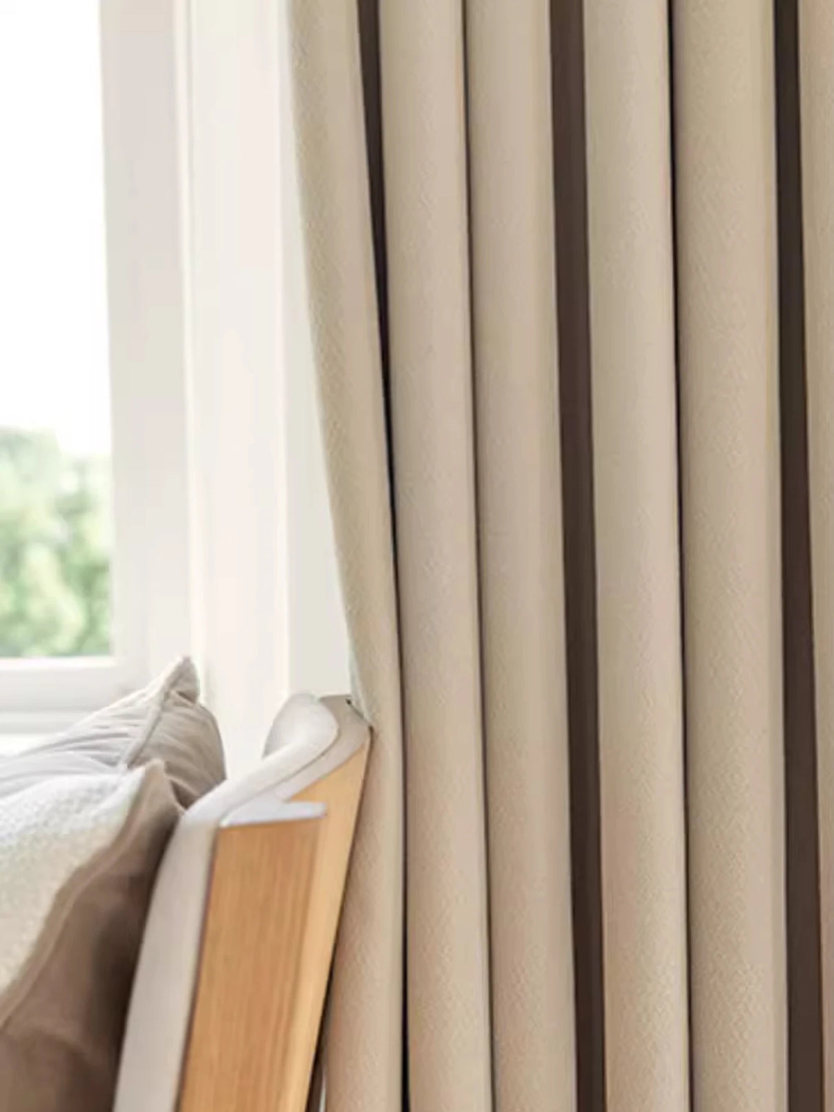 Beige curtains with brown stripes in a room with a window and light-colored bedding.