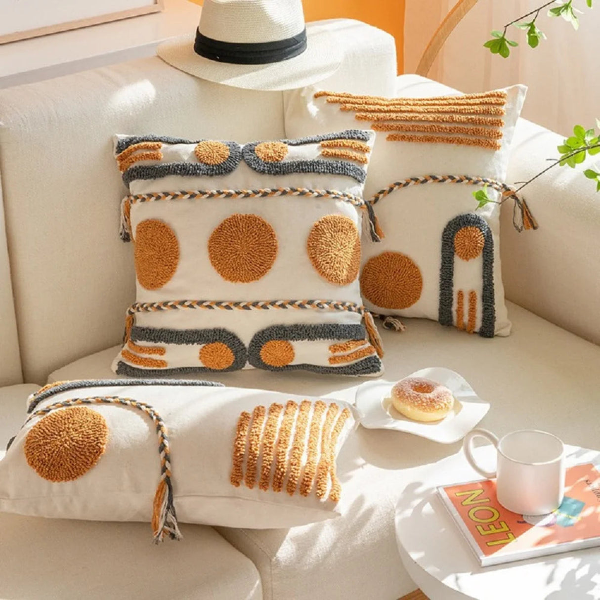 Decorative pillows with circular patterns on a beige sofa with a small table holding a donut and coffee cup.