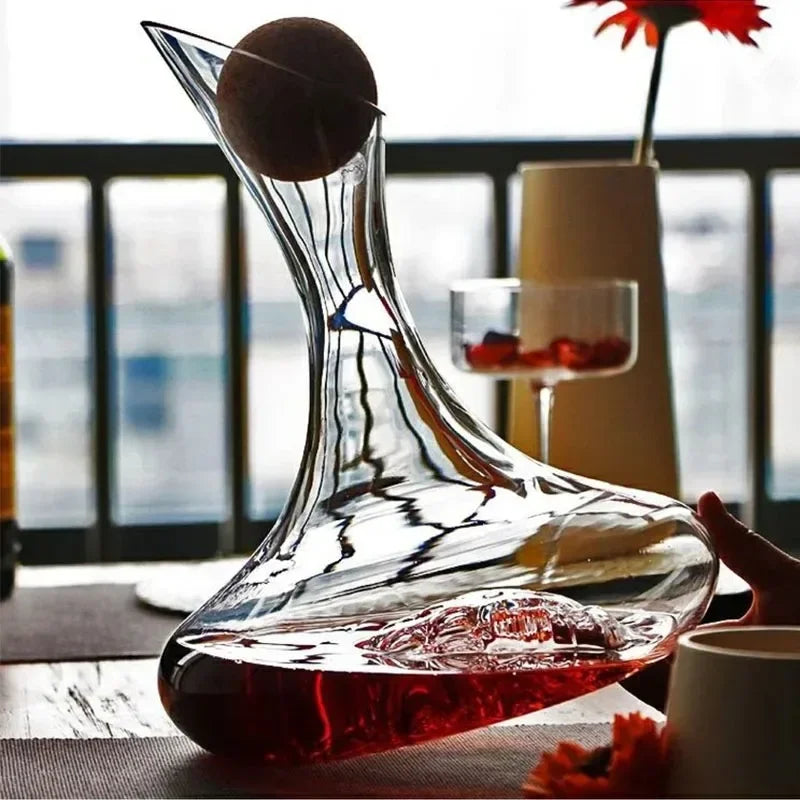 Clear glass wine decanter with red liquid on a table with a blurred background