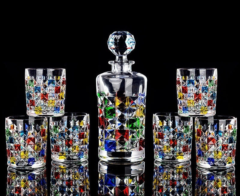 Set of colorful hand-painted glasses with a central decanter on a black background