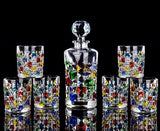 Set of colorful hand-painted glasses with a central decanter on a black background