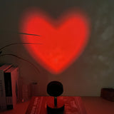 Red heart projection on a wall with books and a lamp in the foreground