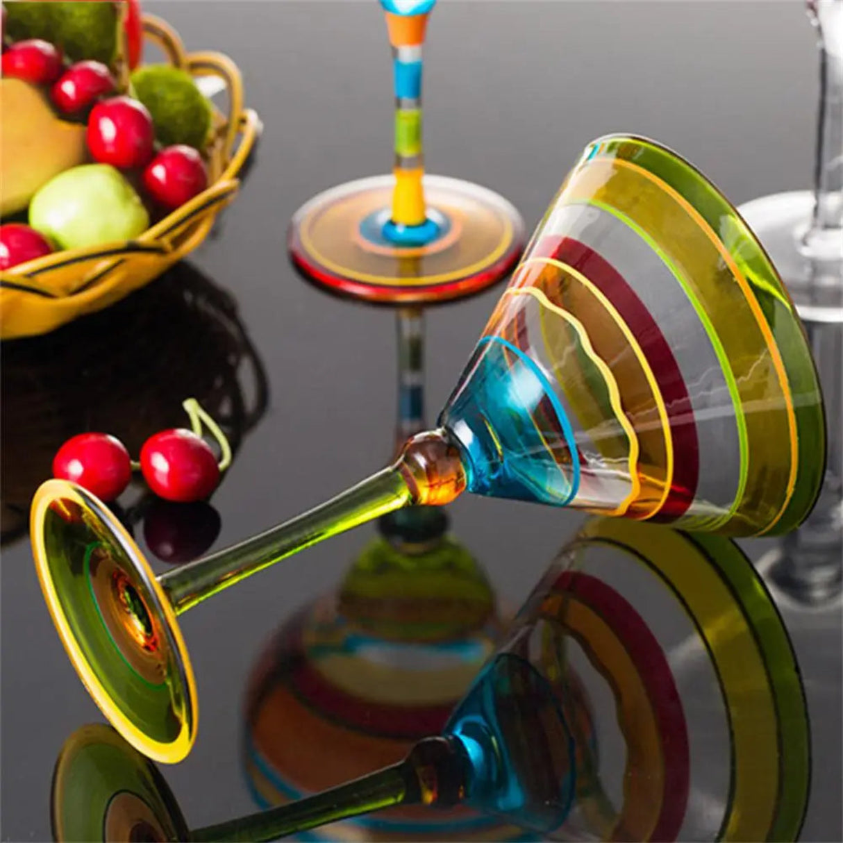 Colorful glass cocktail shaker on a reflective surface with fruits in the background