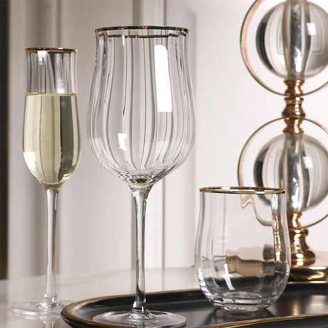 Set of glassware including a flute, wine glass, and bowl on a reflective surface with a neutral background.