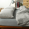 Bed with checkered bedding and pillows in a bedroom setting.