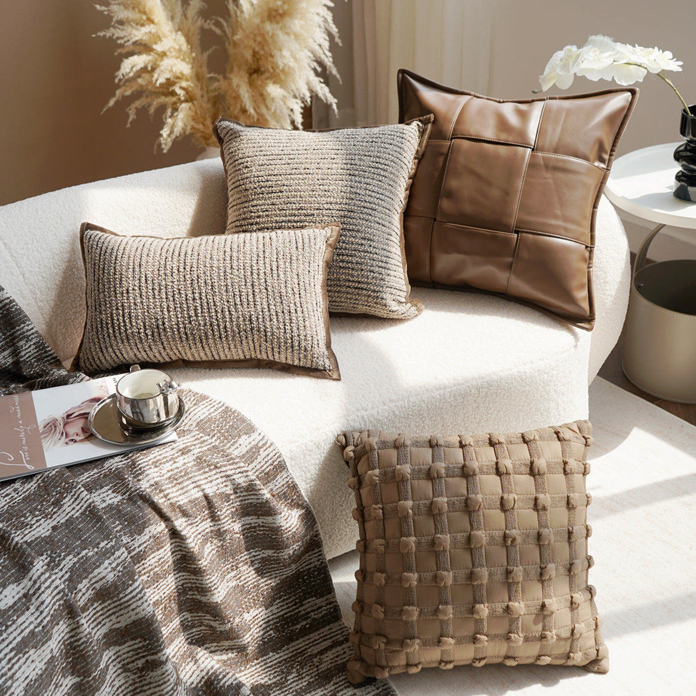 Decorative pillows on a sofa with a cup and saucer, and a plant in the background.