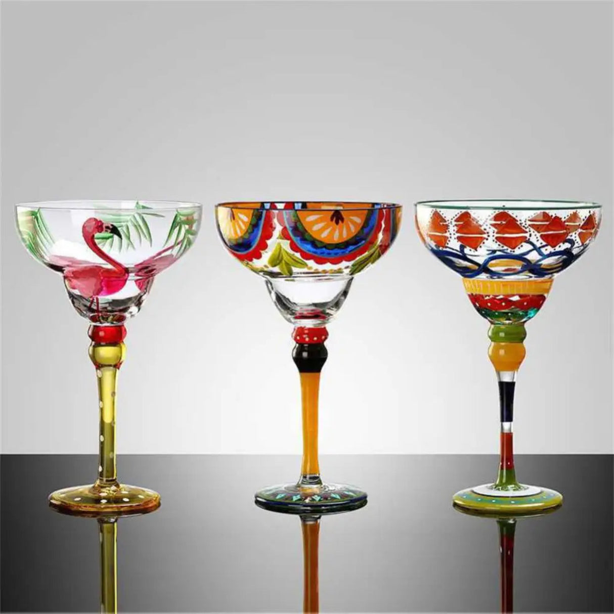 Three colorful glass goblets with artistic designs on a reflective surface.