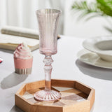 Pink glass candle holder on a wooden tray with a blurred background