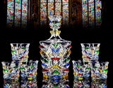 Hand painted whiskey set with colorful design against a stained glass window background