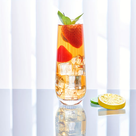 Glass of iced tea with strawberries and lemon slices on a white background