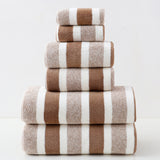 Stack of brown and white striped towels on a light gray background