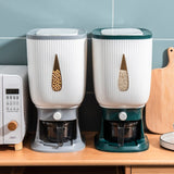 Two kitchen appliances on a wooden surface with a microwave in the background.
