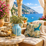 A styled outdoor patio scene with a wicker armchair draped in cream fabric, featuring a decorative throw pillow with a teal and gold palm leaf pattern. In the foreground, a round stone table holds a blue-and-white striped vase with greenery, candles, and small accessories.