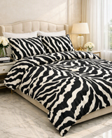 A bed dressed in a black and white zebra-print duvet cover and matching pillow shams, styled in a bright bedroom with a cream tufted headboard, bedside lamp, flowers, and marble flooring. A 'Made with AI' badge appears in the top right corner.