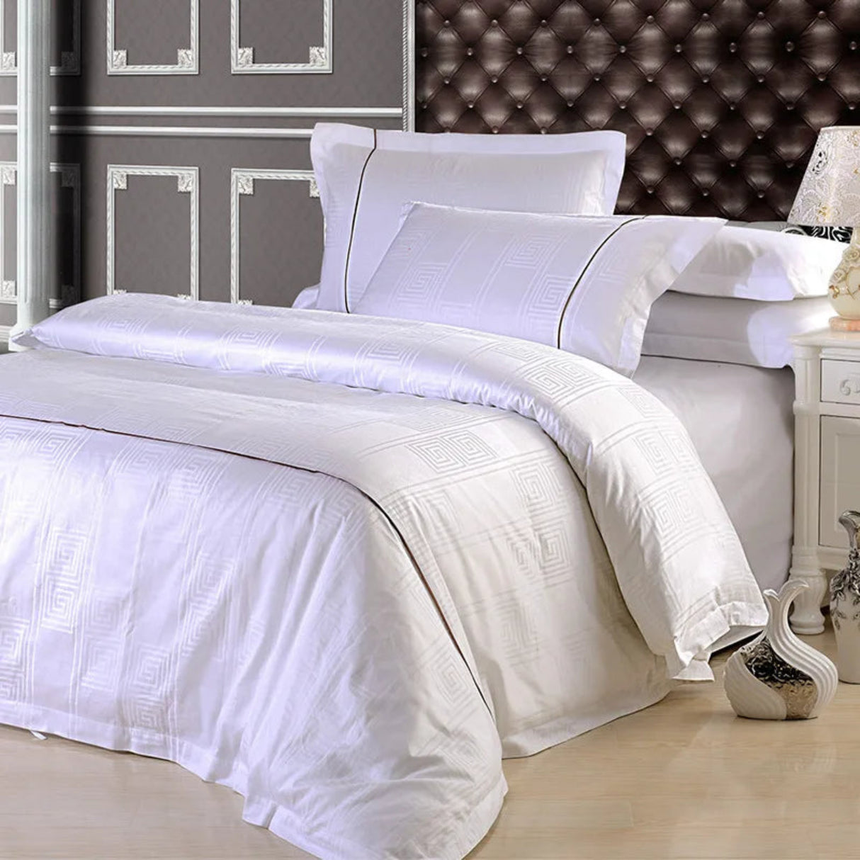 White bedding set on a bed with a decorative headboard.
