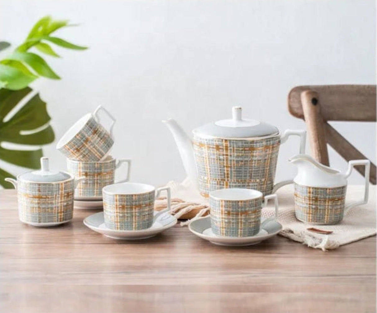 Tea set with plaid design on a wooden table with a plant in the background