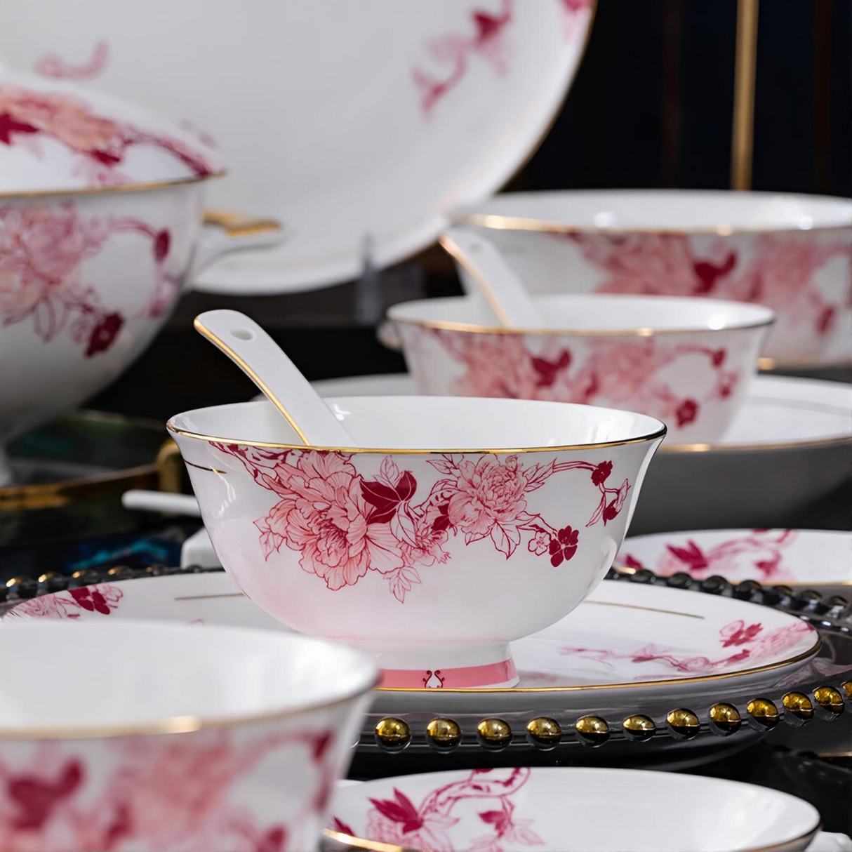 Set of white ceramic bowls with pink floral patterns on a decorative stand.