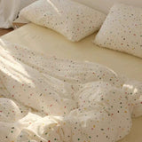 White bedding set with colorful speckles on a bed