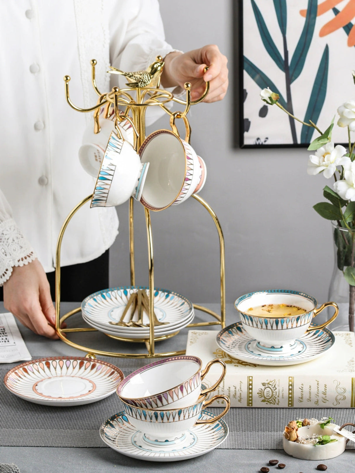 Tea set with cups and saucers on a decorative stand against a neutral background