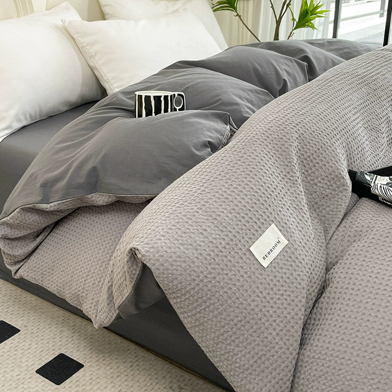 Gray textured comforter on a bed with visible brand label