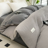 Gray textured comforter on a bed with visible brand label