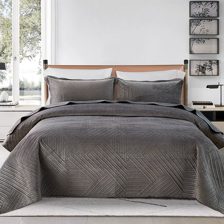 Gray quilted bedding set on a bed in a bedroom with decor elements.