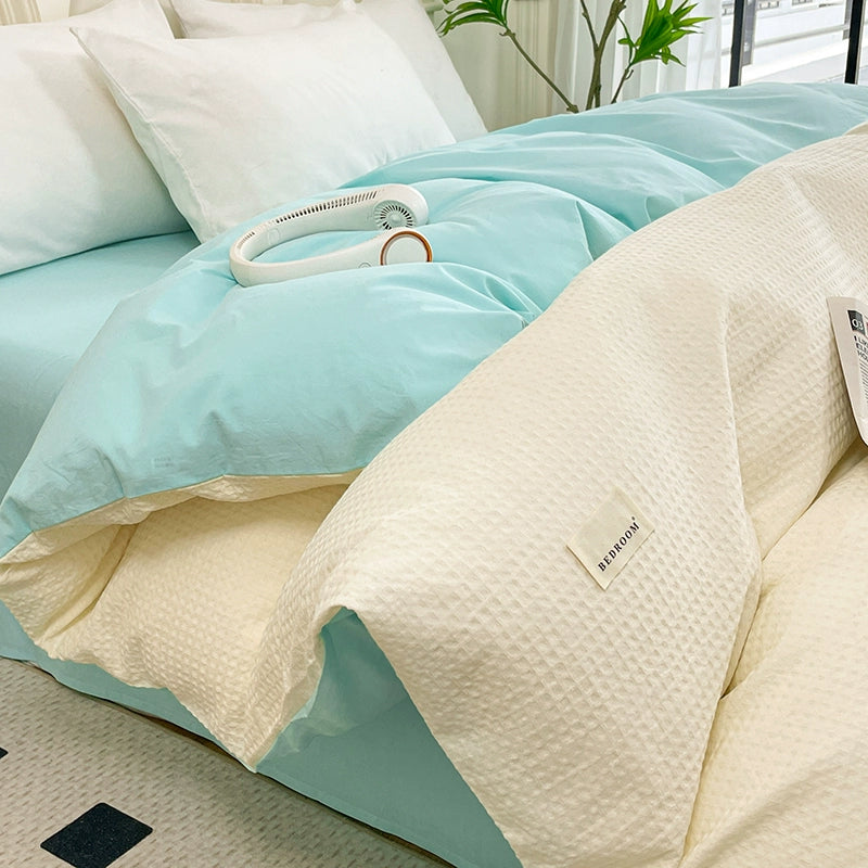 Light blue comforter and beige pillow on a bed with a visible brand label.