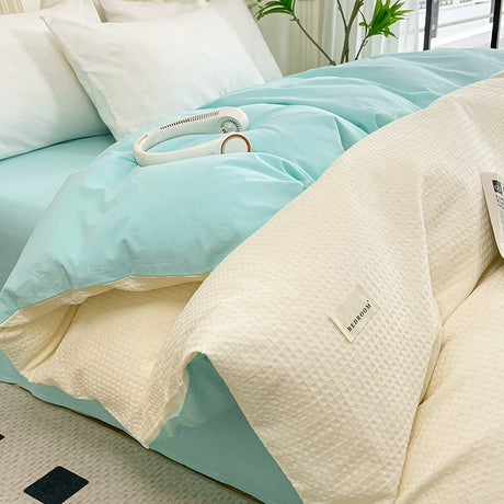 Light blue comforter and beige pillow on a bed with a visible brand label.