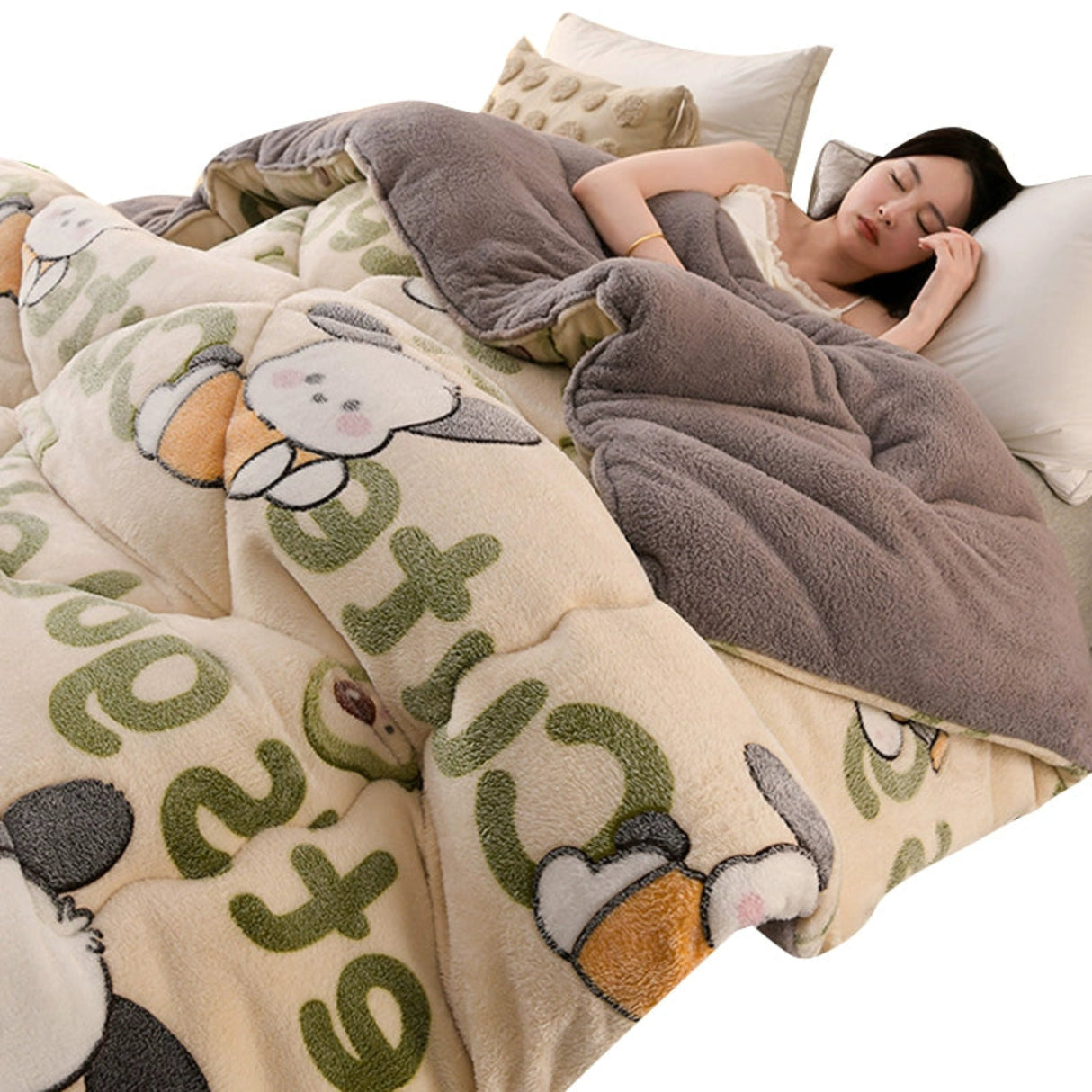 Woman lying in bed under a plush gray blanket with cartoon animal designs on a beige comforter.