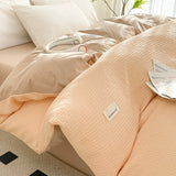 Pink textured comforter on a bed with a visible brand label.