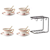 Set of four ceramic tea cups with saucers and a black metal shelf on a white background