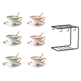 Set of six ceramic teacups with saucers and a black metal rack on a white background