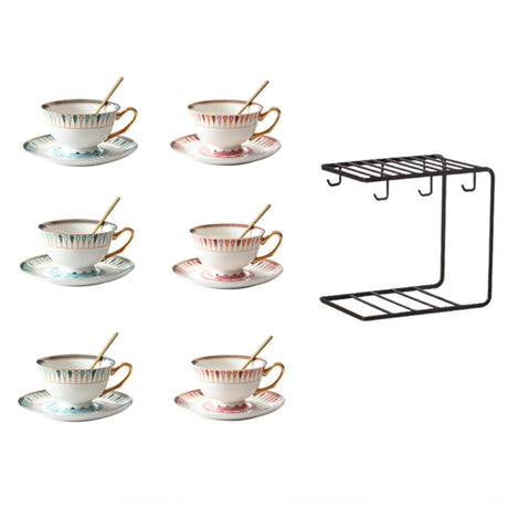 Set of six ceramic teacups with saucers and a black metal rack on a white background