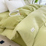 Light green bedding set with a brand label on a bed.