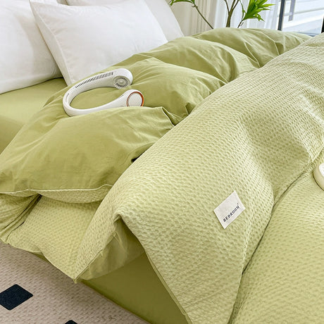 Light green bedding set with a brand label on a bed.