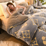 Woman lying on a bed with a patterned gray and beige blanket