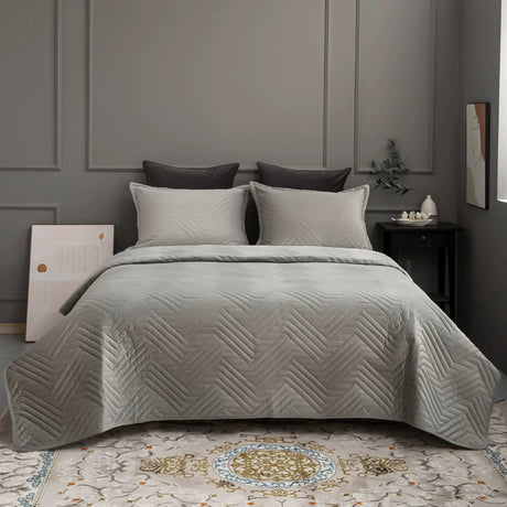 Gray quilted coverlet on a bed in a bedroom setting with gray walls and decorative elements.