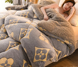 Person lying on a bed with a patterned gray and beige blanket