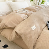 Beige textured comforter on a bed with a visible brand label.