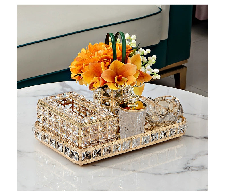 Decorative tray with crystal accents on a marble surface, featuring a small floral arrangement.