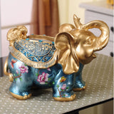 Decorative elephant figurine with gold accents and floral designs on a table.