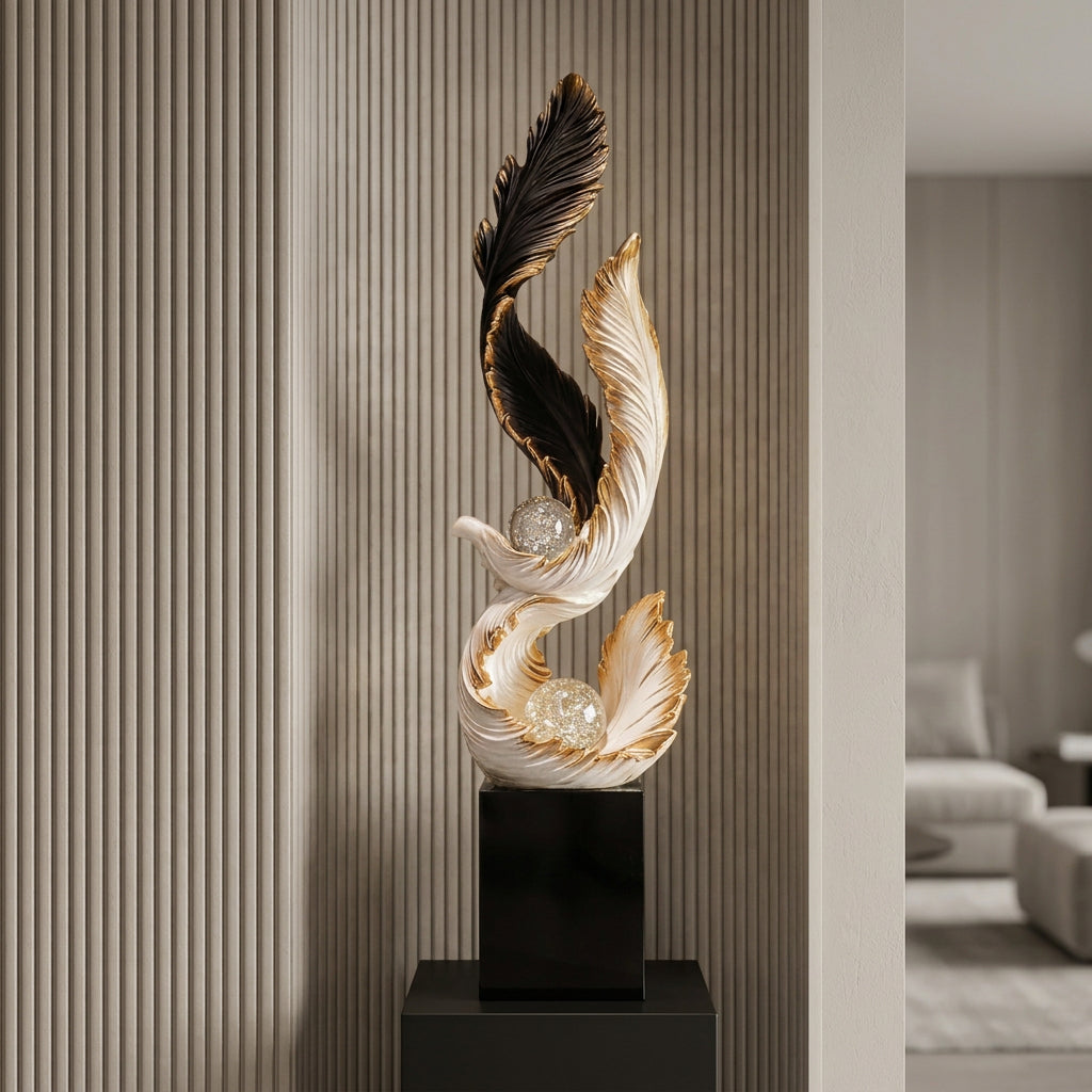 A decorative sculptural bird figure on a black pedestal, shown in an interior setting with wood slat walls and a window in the background. The sculpture is primarily white and black with metallic gold feather accents and clear crystal-like spheres.