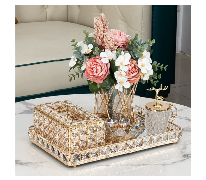 Decorative tray with a vase of flowers and decorative items on a marble surface.