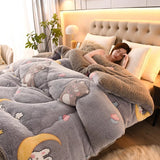 Woman lying on a bed under a gray plush blanket with cartoon designs in a cozy bedroom.
