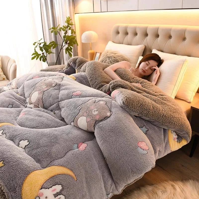 Woman lying on a bed with a gray cartoon-patterned comforter in a cozy bedroom.