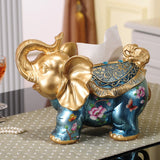 Decorative elephant figurine with gold and blue colors on a table.