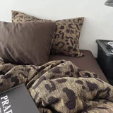 Camouflage-patterned blanket and pillows on a sofa with a side table in the background.