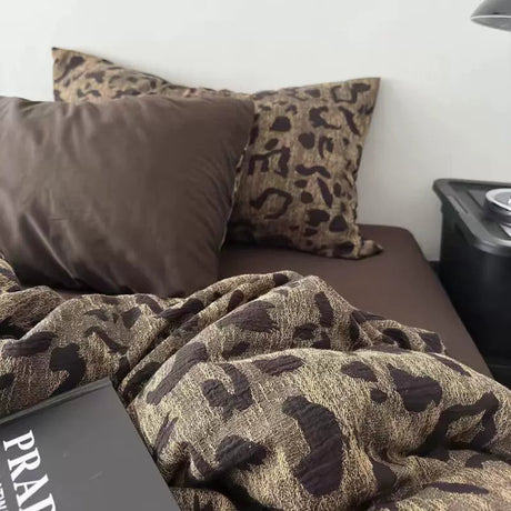 Camouflage-patterned blanket and pillows on a sofa with a side table in the background.